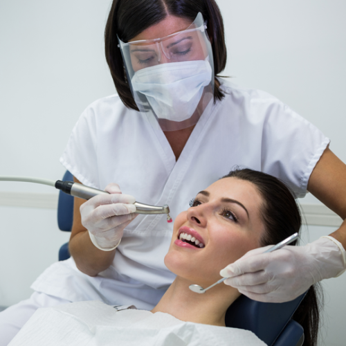 dentist-examining-female-patient-with-tools