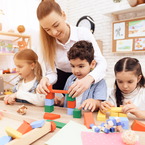 kids-playing-with-wooden-cubes-and-teacher-is-helping-themkids-playing-with-wooden-cubes-and-teacher-is-helpig-t