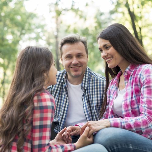 padre-sonriente-que-mira-su-hija-durante-sentarse-en-parque